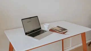 Laptop, kawa i książki na białym biurku